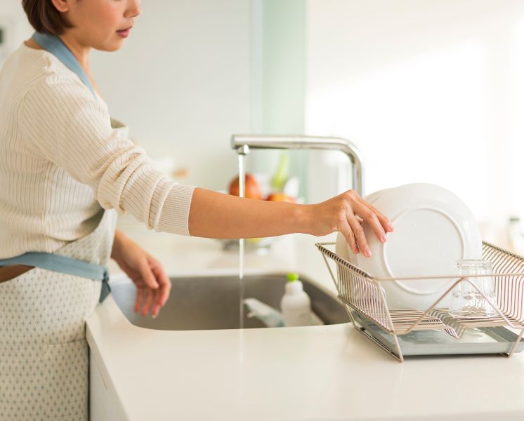 mulher lavando louça na pia da cozinha